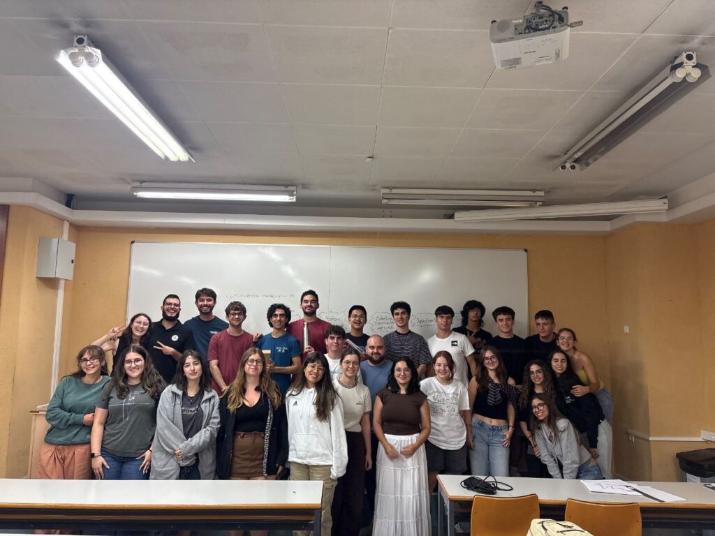 oto de grupo de las personas participantes en las Jornadas Mistral 2026, posando en un aula delante de una pizarra.